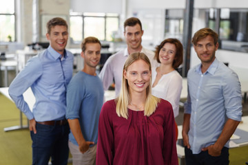 lächelnde blonde frau mit einem team im büro