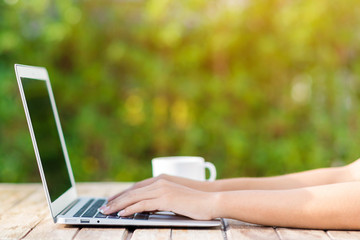 Woman hand using laptop computer on wooden table