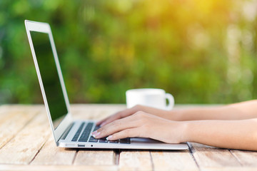 Woman hand using laptop computer on wooden table