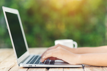 Woman hand using laptop computer on wooden table