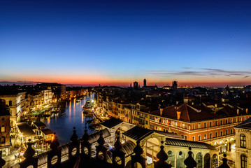 Obraz premium Grand Canal, Rialto Bridge, and the city of Venice view from above at sunset. The picture is taken from Fondaco dei Tedeschi
