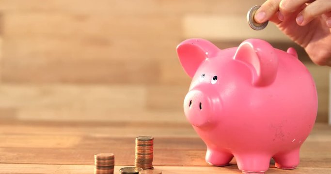 Close-up of woman putting coin in piggy bank 4k