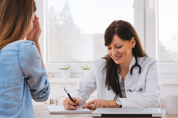 Doctor writing and smiling with patient