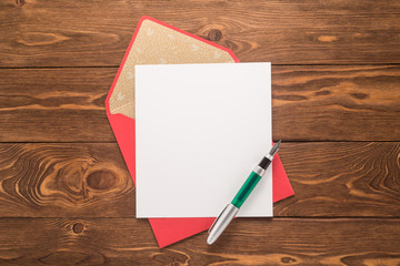 Blank paper, envelope and pen on a wooden background 