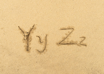 alphabet letters handwritten in sand on beach