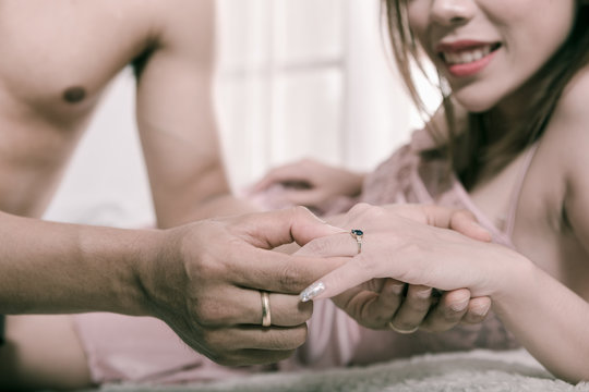 Men are wearing a ring to a beautiful woman in the bedroom.