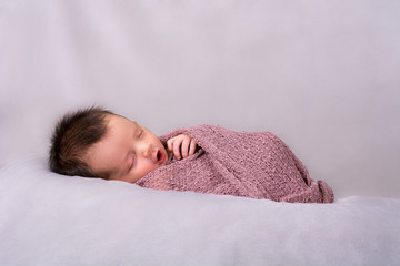 Beautiful newborn baby girl swaddled in a knit wrap