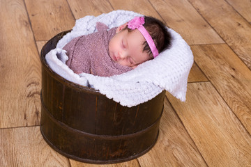 Beautiful newborn baby girl asleep in a bucket