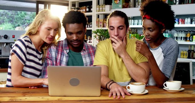 Group of friends using laptop while having cup of coffee in cafÃ© 4k
