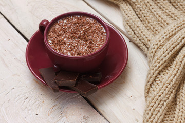 Obraz na płótnie Canvas Milk chocolate in a cup on a saucer on a light wooden background