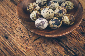 quail eggs on wooden plate on wooden background