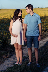 Man and pregnant lady look at each other while they stand on the