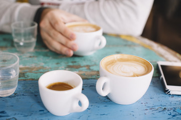 People talking in the cafe while having some fresh coffee (two cappuccinos and one espresso)