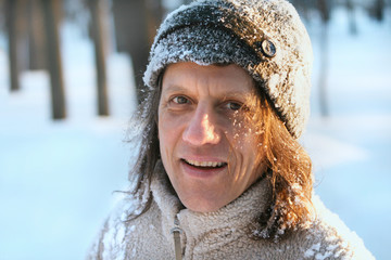 Счастливый мужчина с длинными волосами в парке зимой