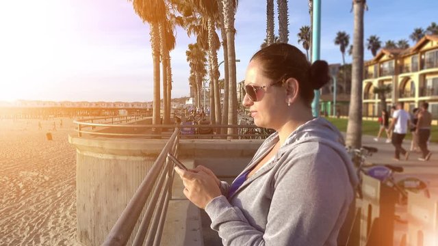 Video of woman using mobile phone on the boardwalk in 4K. High quality video of woman using mobile phone on the boardwalk in 4K