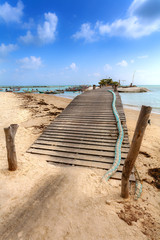 Wooden bridge on the beach with fishing boats, sea with turquois