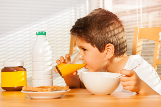 Little boy drinking orange juice at breakfast