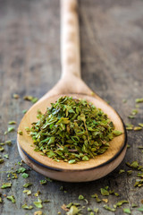 Oregano on wooden spoon on wooden background

