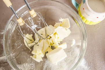 Organic batter in a white bowl isolated on a kitchen table with mixer beaters.