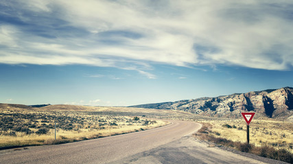 Retro color toned road with yield sign, travel concept.