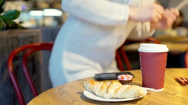 Girl brings herself wooden cutlery while having a breakfast in the bistro, steadycam shot
