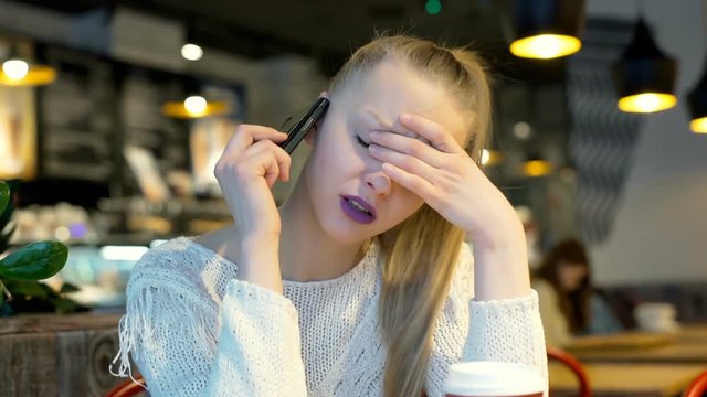 Angry gitl sitting in the bistro and having an argument on cellphone, steadycam shot

