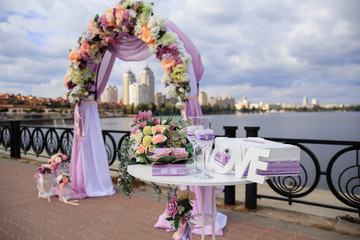 luxury wedding arch on the riverside with purple and pink ribbons