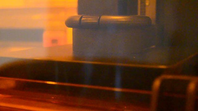 Stereolithography DPL 3d printer create detail and liquid drips, platform slowly move with liquid close-up. Progressive modern additive technology 3D printing, create scaled model by UV polymerization