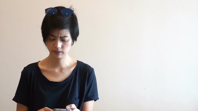 Asian mixed race girl looking at phone and start to get worry for online negative content