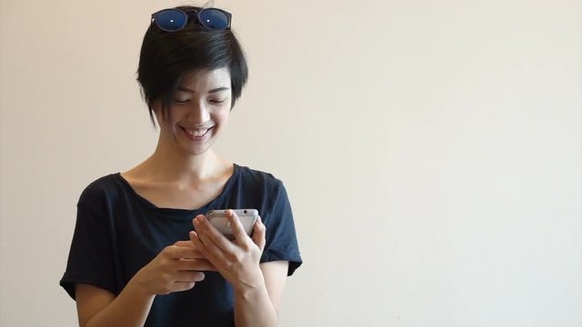 Cool Asian hipster girl with modern look smile and laugh while using smart phone