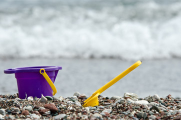 Baby toy bucket and spade on a pebble beach. - 134601673
