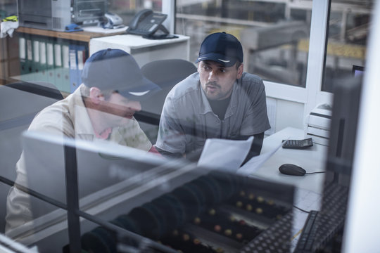 Two workers in factory office discussing