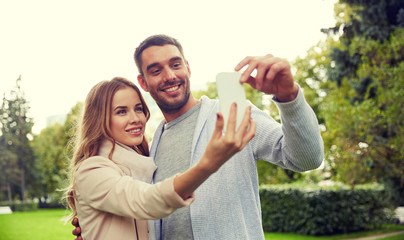 Fototapeta premium happy couple with smartphone taking selfie in park