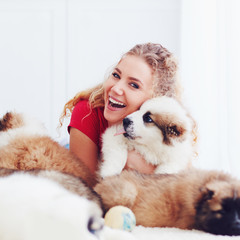 beautiful woman playing with cute caucasian shepherd puppies, dogs