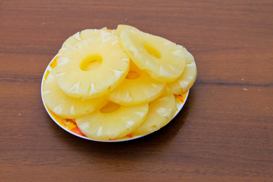 Canned pineapple on a plate on wooden table