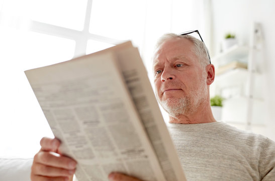 close up of senior man reading newspaper at home