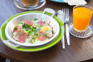 Fried egg in a pan with bread and pork sausage