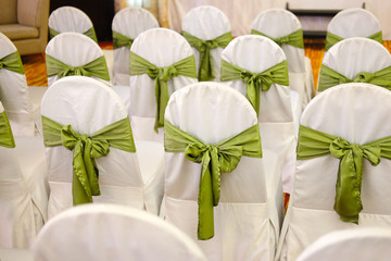 Fototapeta na wymiar Chairs for a party with green covers ribbon and bow