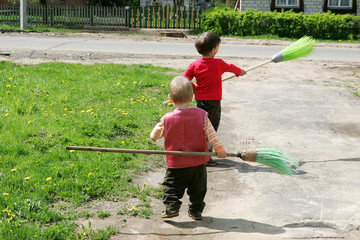 Two boys playing in the street with brooms