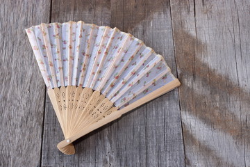 Chinese hand fan on old wooden board background.