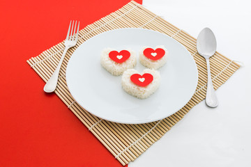 cooked rice heart shapes with a spoon and fork on white dish
