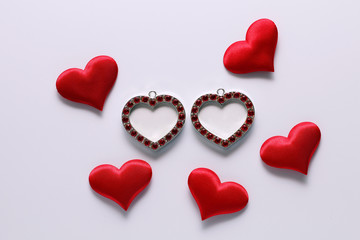 Small photo frames in the form hearts and red plush hearts on a white background.