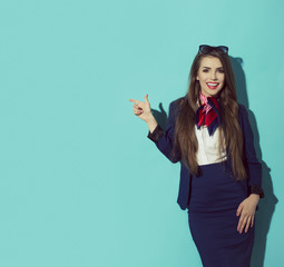 Beautiful elegant brunette female pointing to the left. Space on blue background.
