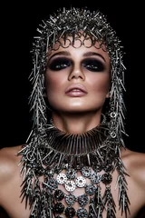  High fashion schoonheidsmodel met metalen hoofddeksels en donkere make-up en blauwe ogen op zwarte achtergrond © khosrork