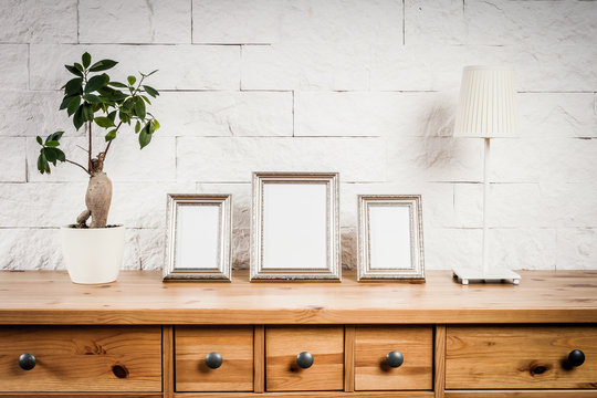 wooden shelf with frames and flower against a brick wall