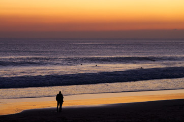 Couple at beach by dusk watching surfers