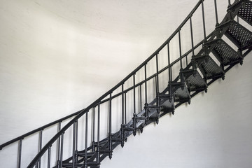 A black wrought iron spiral staircase ascends the interior of the historic Bodie Island Lighthouse at Cape Hatteras National Seashore on the Outer Banks of North Carolina.