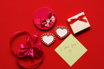 Girl puts on a red table with a note saying "I love you!". On the table lies a lot of gift and toy hearts.
