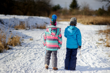 Fototapeta na wymiar Two children of younger school age, boy and girl, admire a winter landscape.