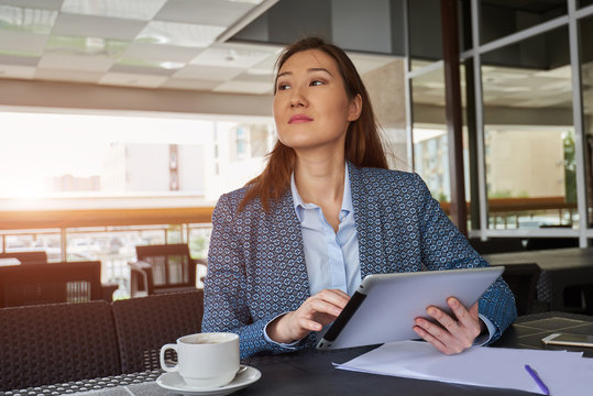 Portrait of young smiling female speak with her friends while chatting via digital tablet device during breakfast in coffee shop,